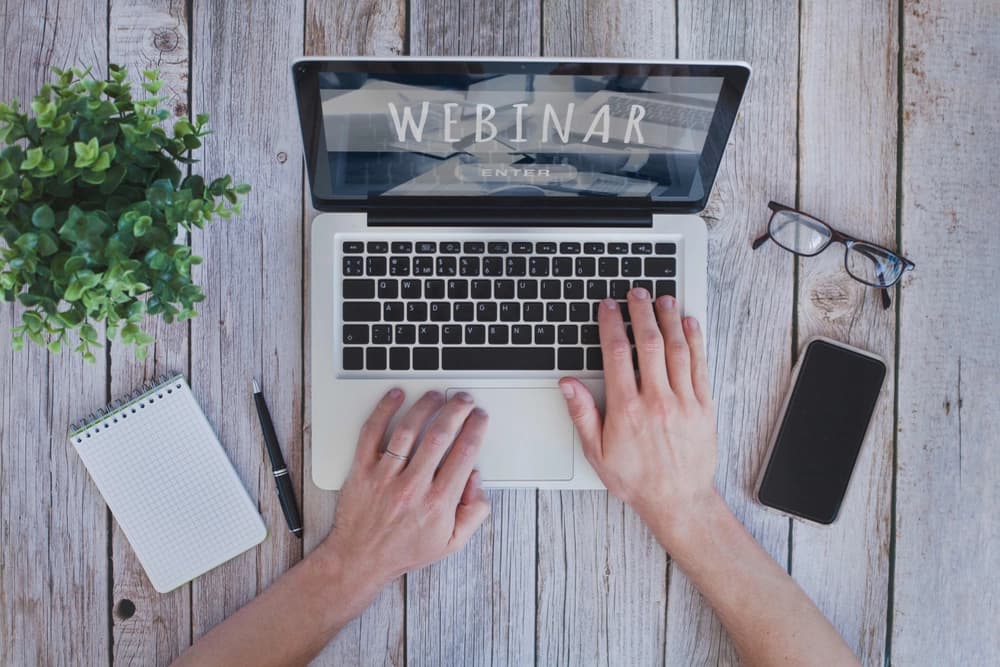 Person sitting at laptop, ready to takes notes during a webinar.